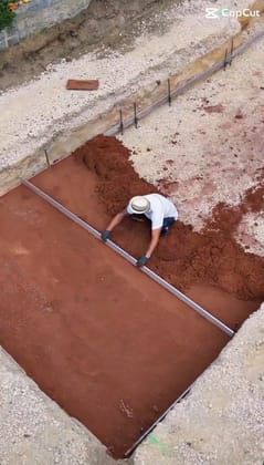 Aushub und Unterbau für einen Pool: Mitarbeiter zieht den Untergrund in der Baugrube ab