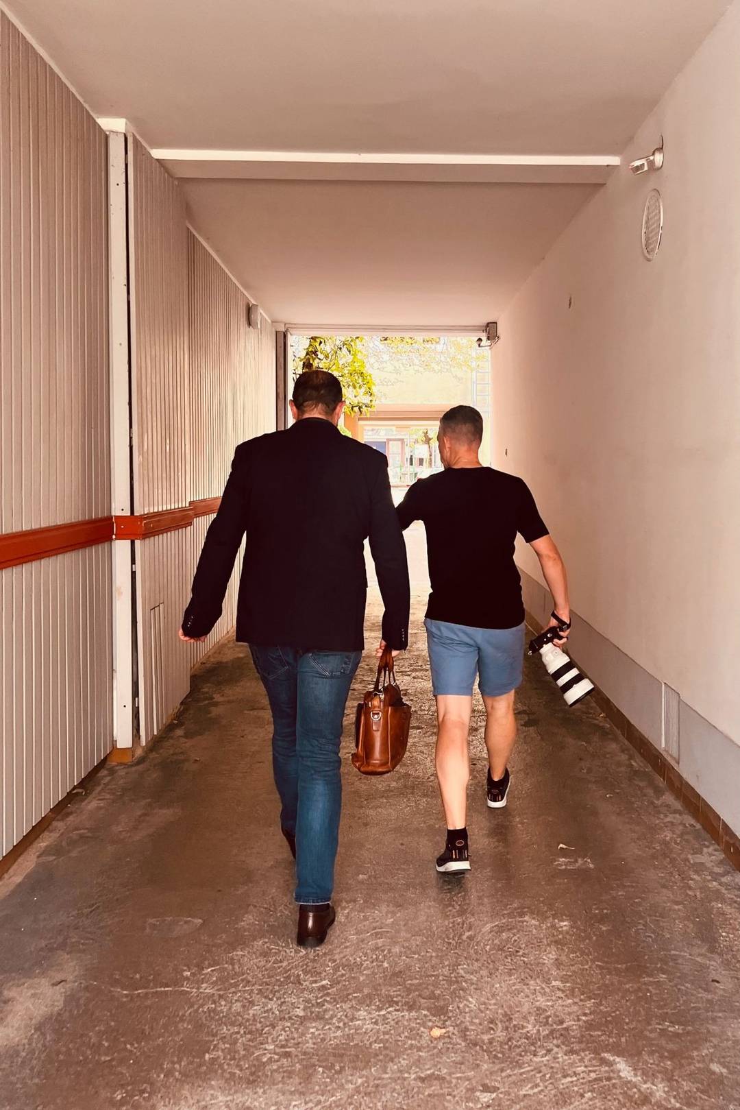 Alex Lörtscher mit Kamera und Teleobjektiv unterwegs zum Fototermin, neben ihm ein Mann im Sakko mit Ledertasche