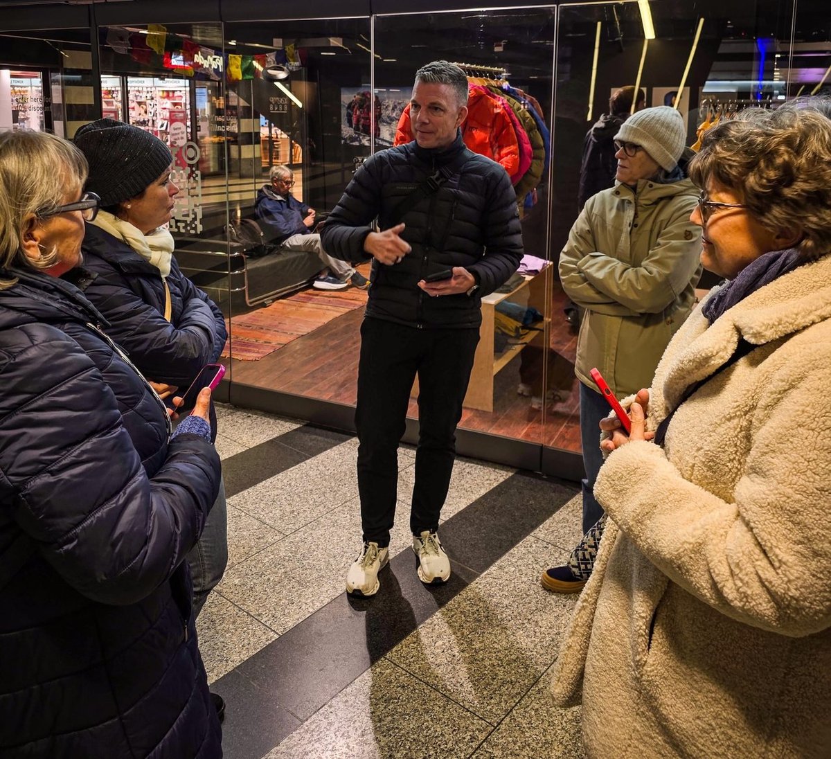 iPhone Kamera-Einstellungen erklärt: Alex Lörtscher zeigt einer Gruppe am Abend etwas am Smartphone