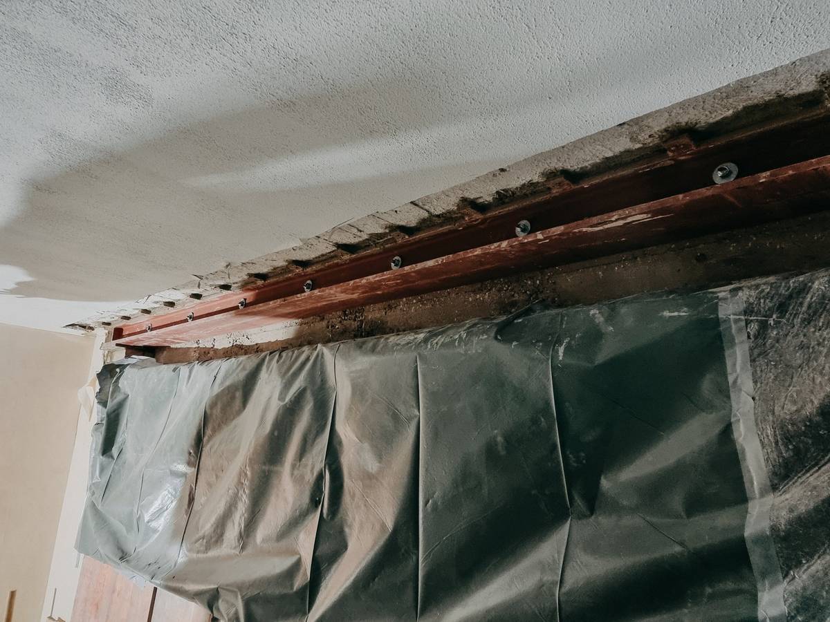 Zwei Handwerker setzen einen Stahlträger in eine Wandöffnung