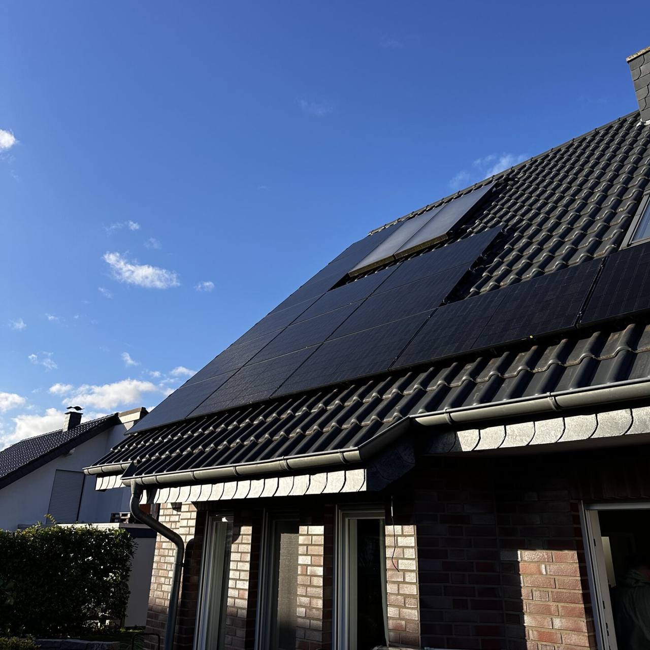 Klinkerhaus mit vollschwarzen Solarmodulen unter blauem Himmel
