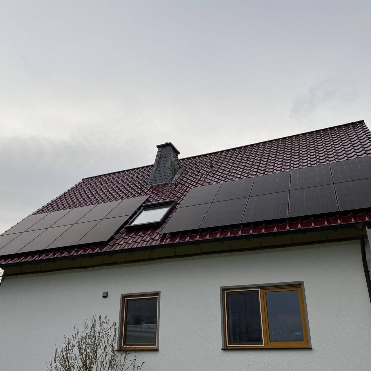 Weißes Haus mit rotem Ziegeldach und Photovoltaikmodulen