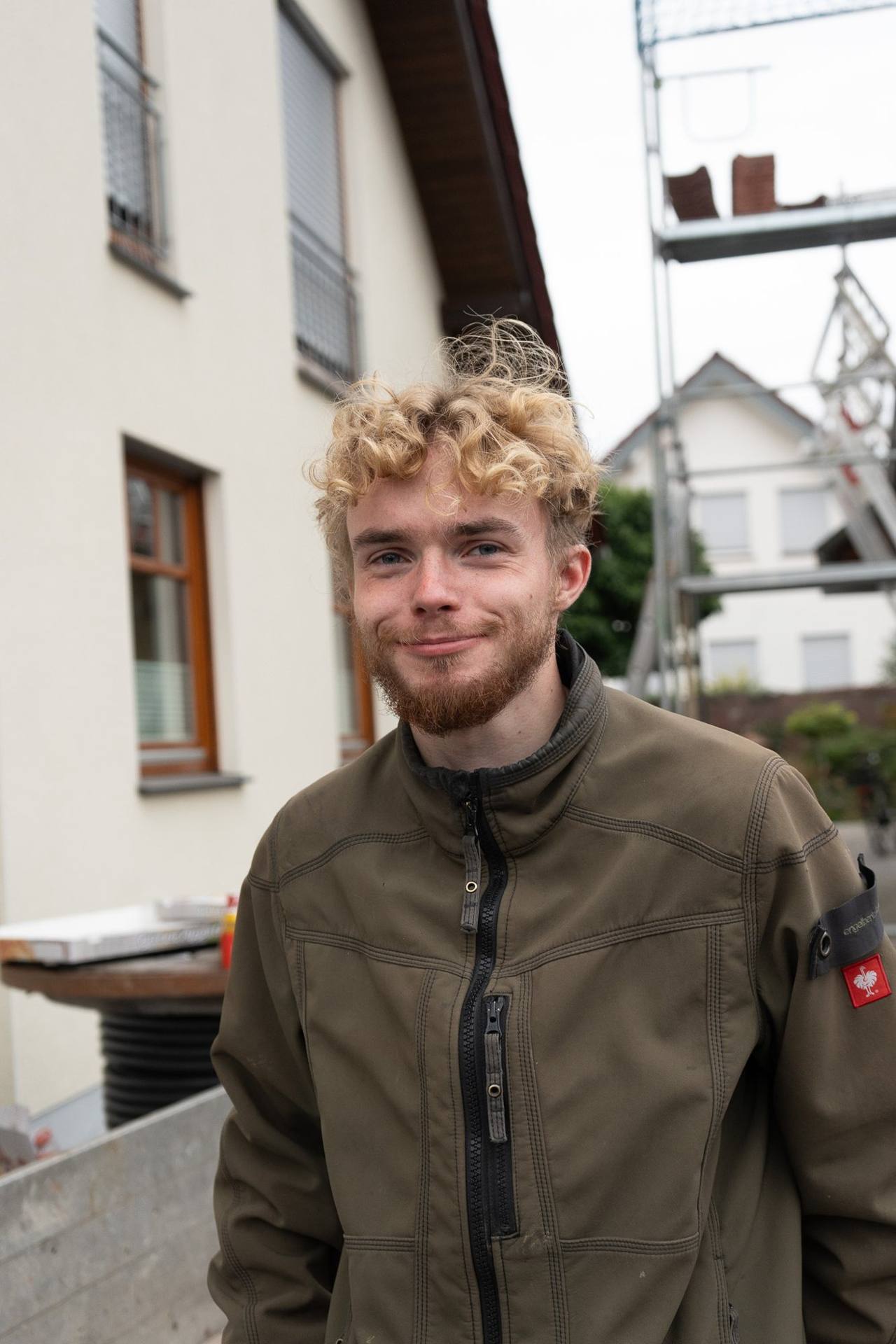 OurSun-Handwerker vor einer Baustelle mit Gerüst