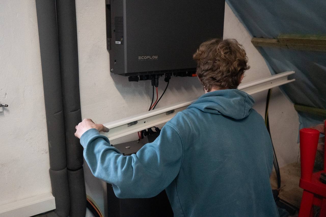 Techniker montiert einen Kabelkanal unter einem EcoFlow-Hybrid-Wechselrichter, darunter der Batteriespeicher