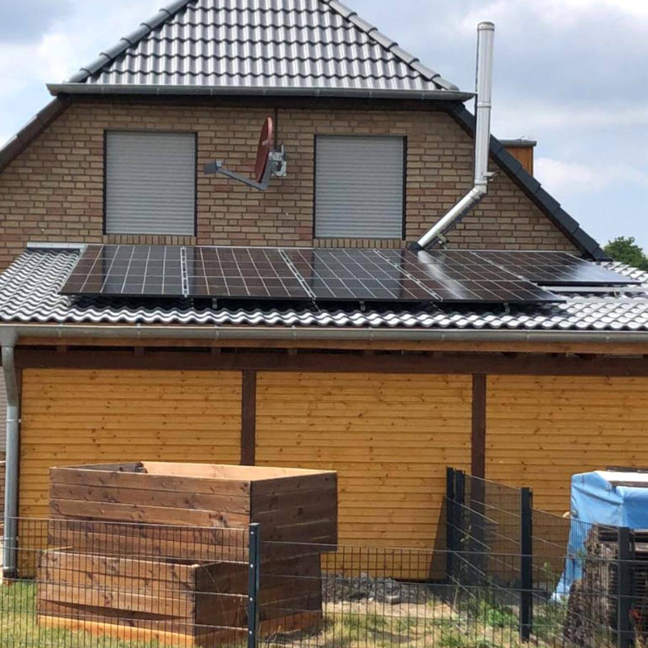 Haus mit Ziegeldach, roter Fassade und Terrasse mit PV-Anlage