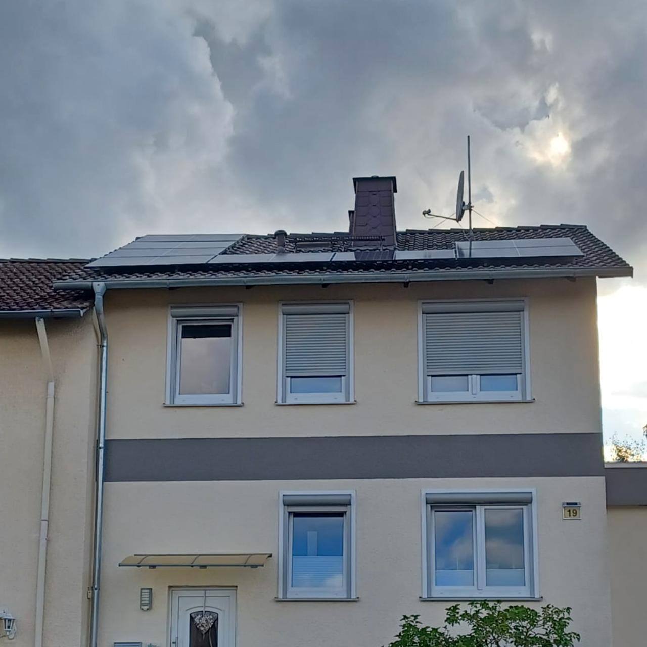 Beiges Mehrfamilienhaus mit Solarmodulen auf dem Dach