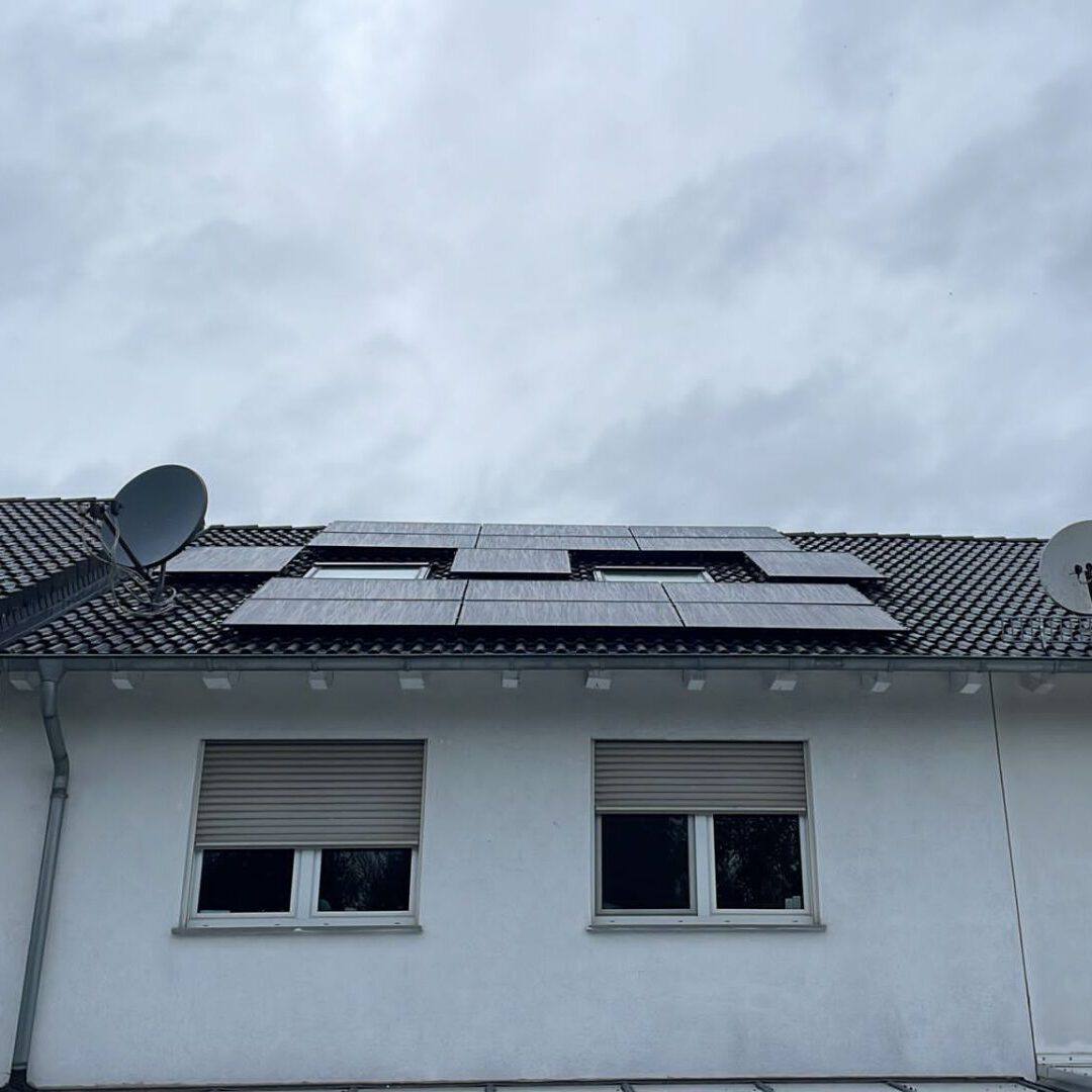 Einfamilienhaus mit Gaube und grauem Dach mit Solarmodulen