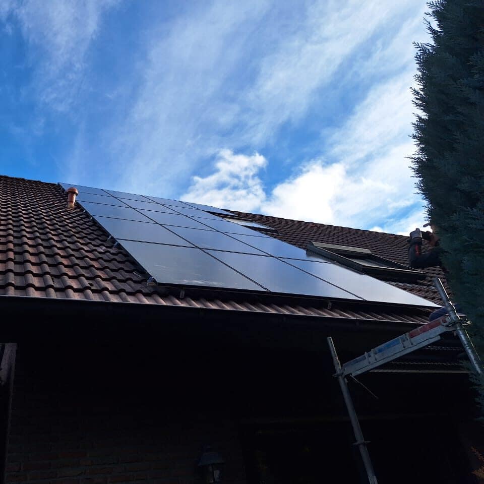 Satteldach mit Solarmodulen vor blauem Himmel aus der Untersicht