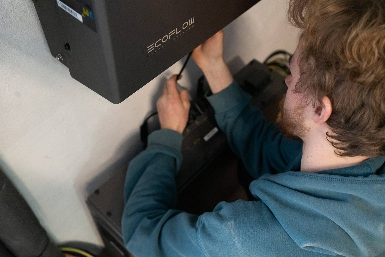Techniker verkabelt einen EcoFlow-Wechselrichter, Blick über die Schulter auf Gerät und Batterie