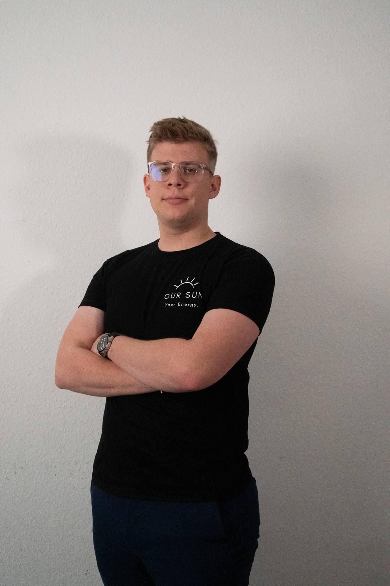 OurSun-Mitarbeiter im Firmen-Shirt mit verschränkten Armen