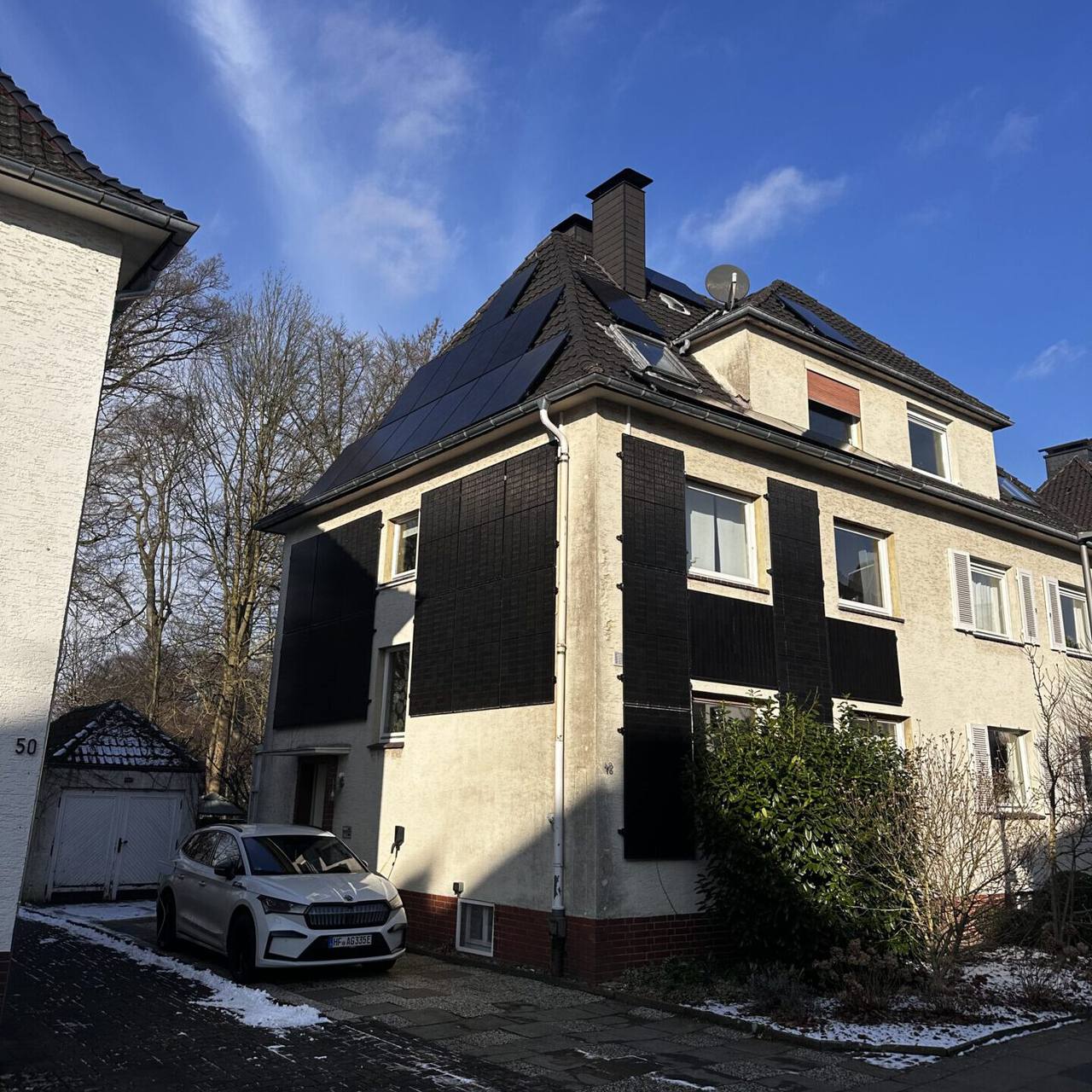Stadthaus mit Photovoltaikanlage und Auto vor der Tür