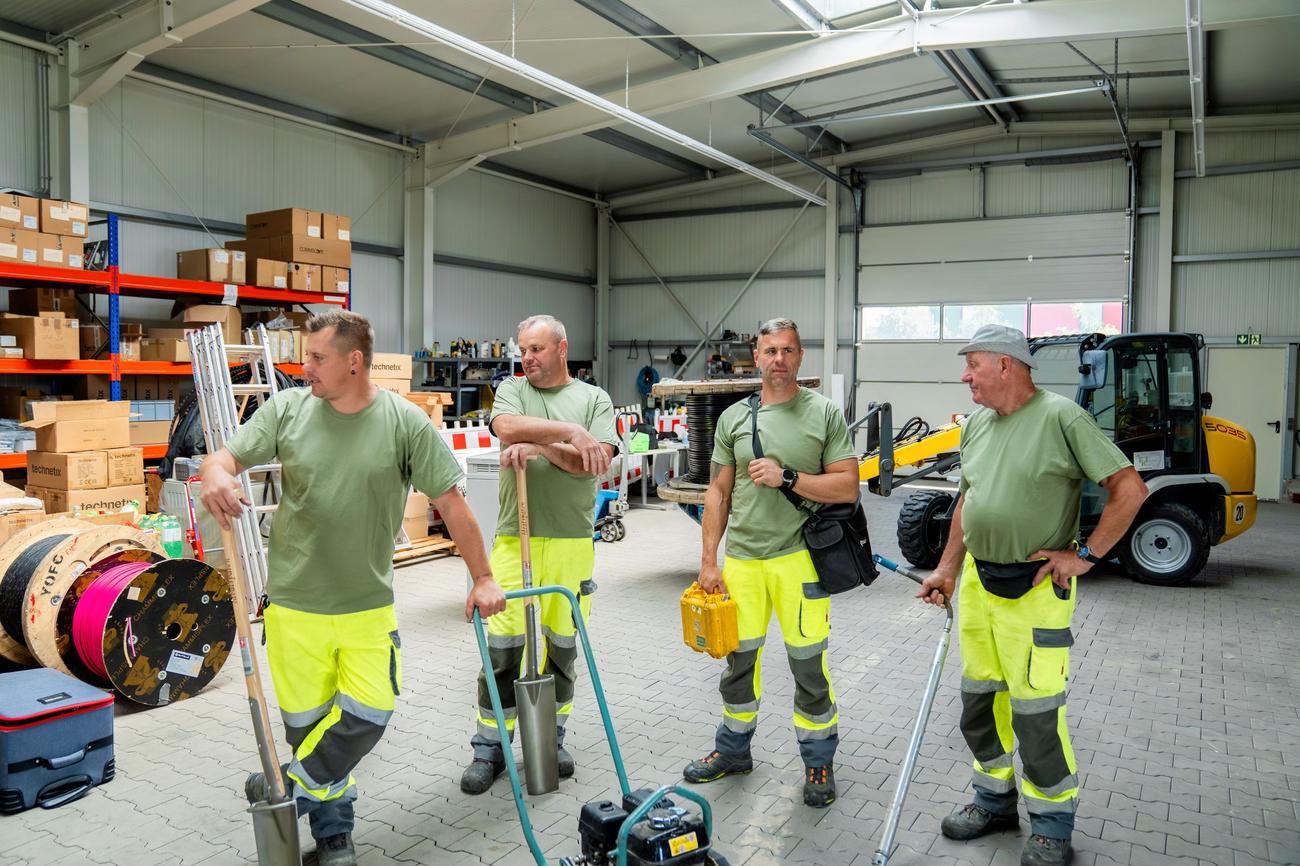Vier Kollegen stehen mit Werkzeug in der Halle, daneben eine Kabeltrommel.