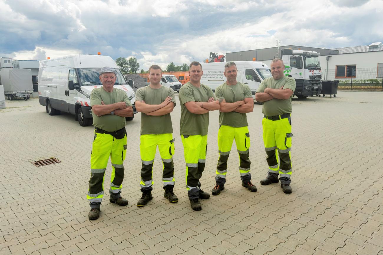 Fünf Kollegen stehen mit verschränkten Armen auf dem Betriebshof.