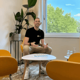 Ein lächelnder Mann sitzt auf einem gelben Stuhl