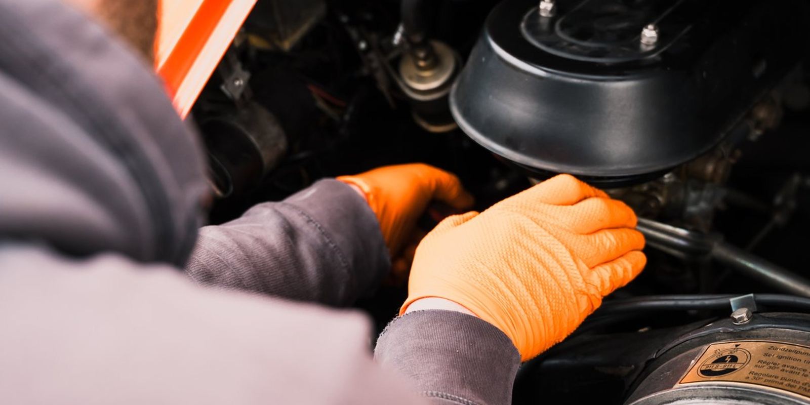 Mechaniker arbeitet in der Werkstatt von DEINELFER am Motor eines klassischen Porsche 911