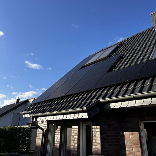 Klinkerhaus mit Full-Black-Solarmodulen unter blauem Himmel