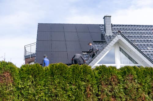 Monteure verlegen die letzten Module auf einem Satteldach