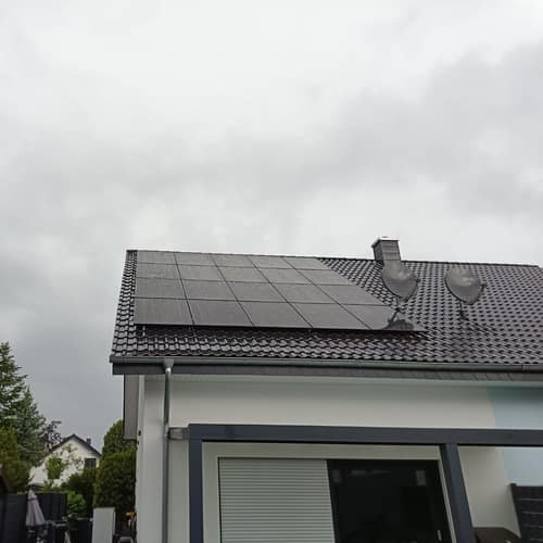 Weißes Haus mit grauem Dach und Solarmodulen