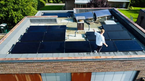 Flachdach mit schwarzen Solarmodulen aus der Drohnenperspektive
