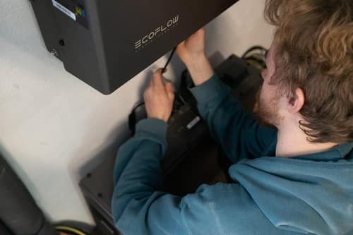 Techniker verkabelt einen EcoFlow-Wechselrichter oberhalb des Batteriespeichers