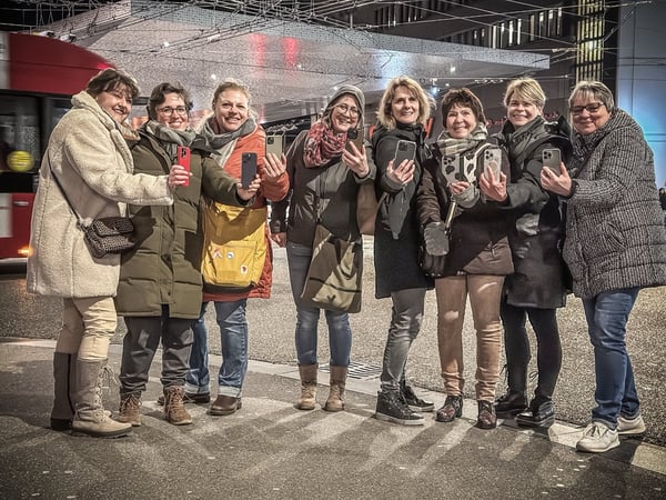 iPhone Kamera-Einstellungen: Alex Lörtscher zeigt einer Gruppe am Abend etwas am Smartphone