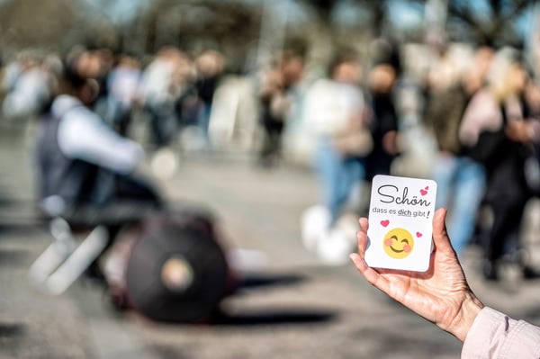 Stellensuche ab 50: Hand hält in einer Menschenmenge eine Karte mit der Aufschrift Schön dass es dich gibt