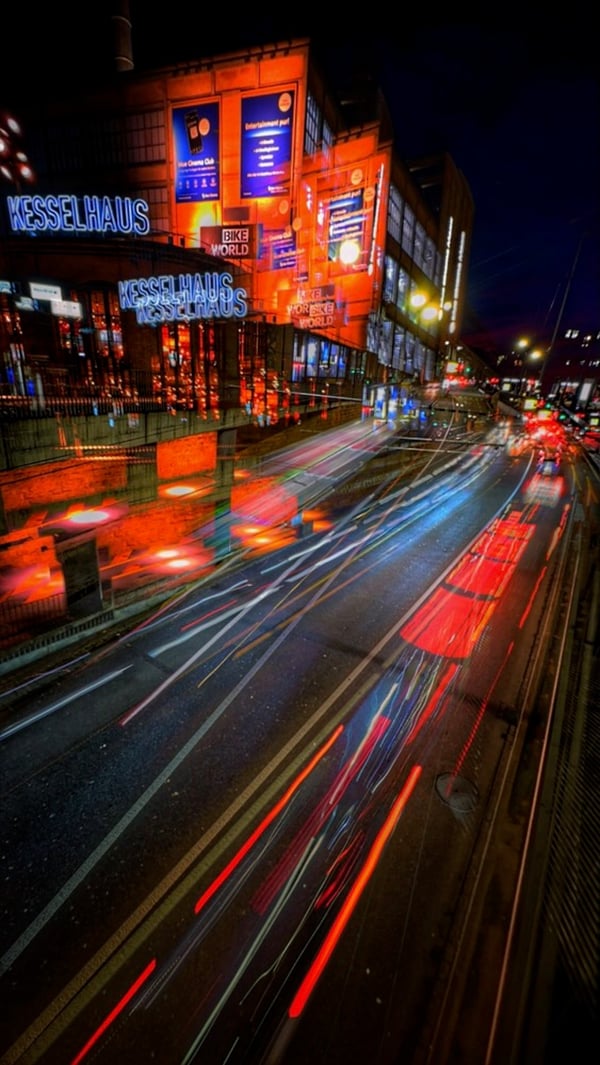 Lichtspuren des Verkehrs vor einer beleuchteten Industriehalle