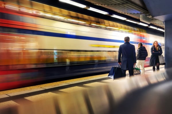 Einfahrender Zug als Mitzieher, wartende Person scharf, mit dem Smartphone fotografiert