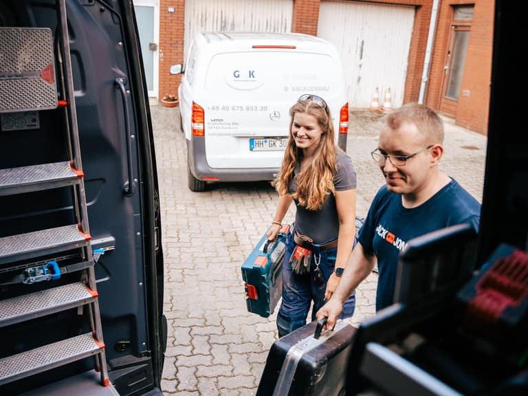 Team der G+K Sanitärtechnik mit Ausrüstung vor den Firmenfahrzeugen in Hamburg