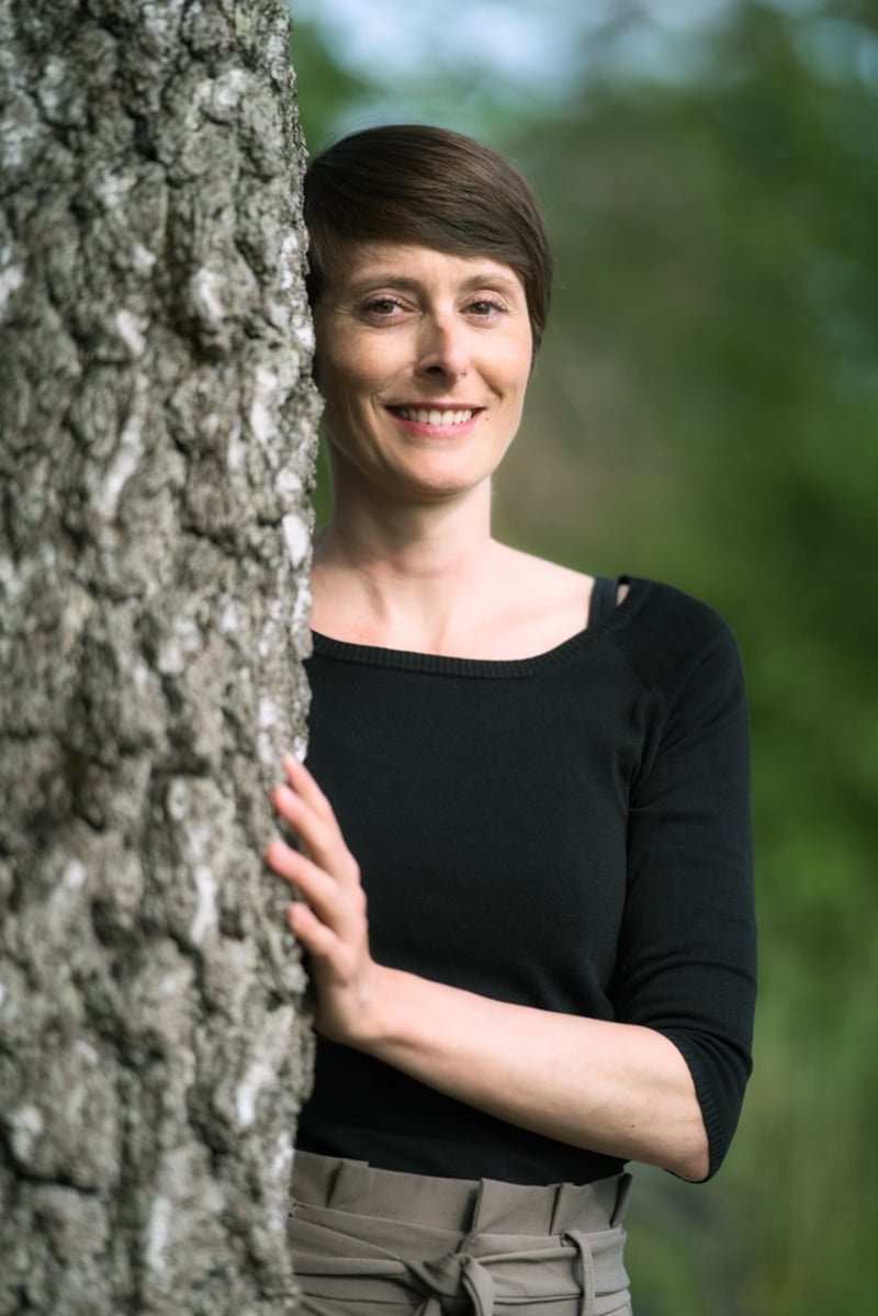 Porträt im Freien: Frau in schwarzem Oberteil an einem Baum
