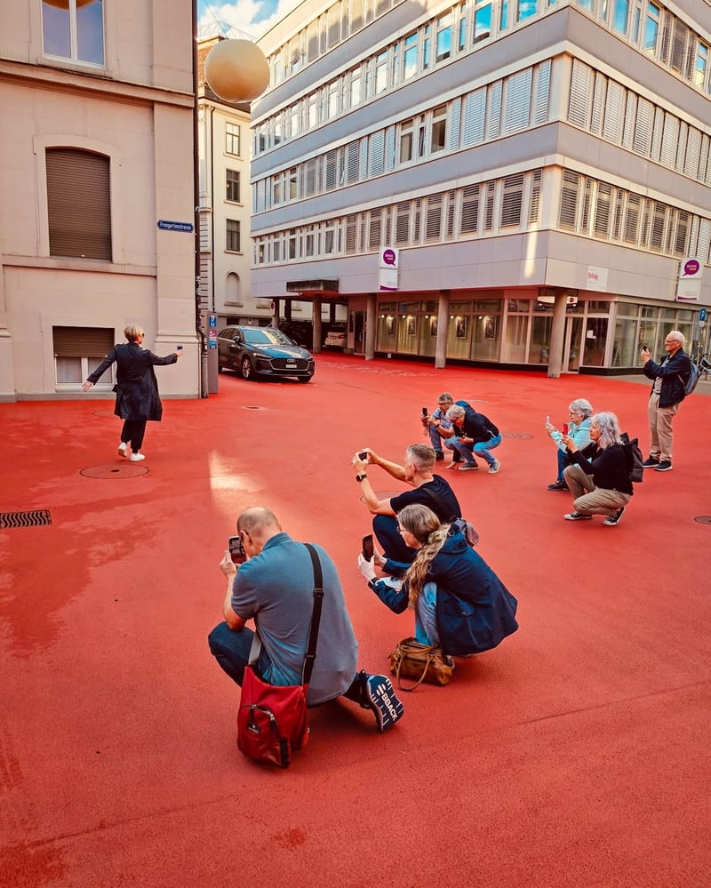 Teilnehmer in der Hocke beim Fotografieren auf einem roten Platz