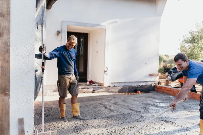 Mitarbeiter der Bauunternehmung Drews verteilen Beton für eine Bodenplatte