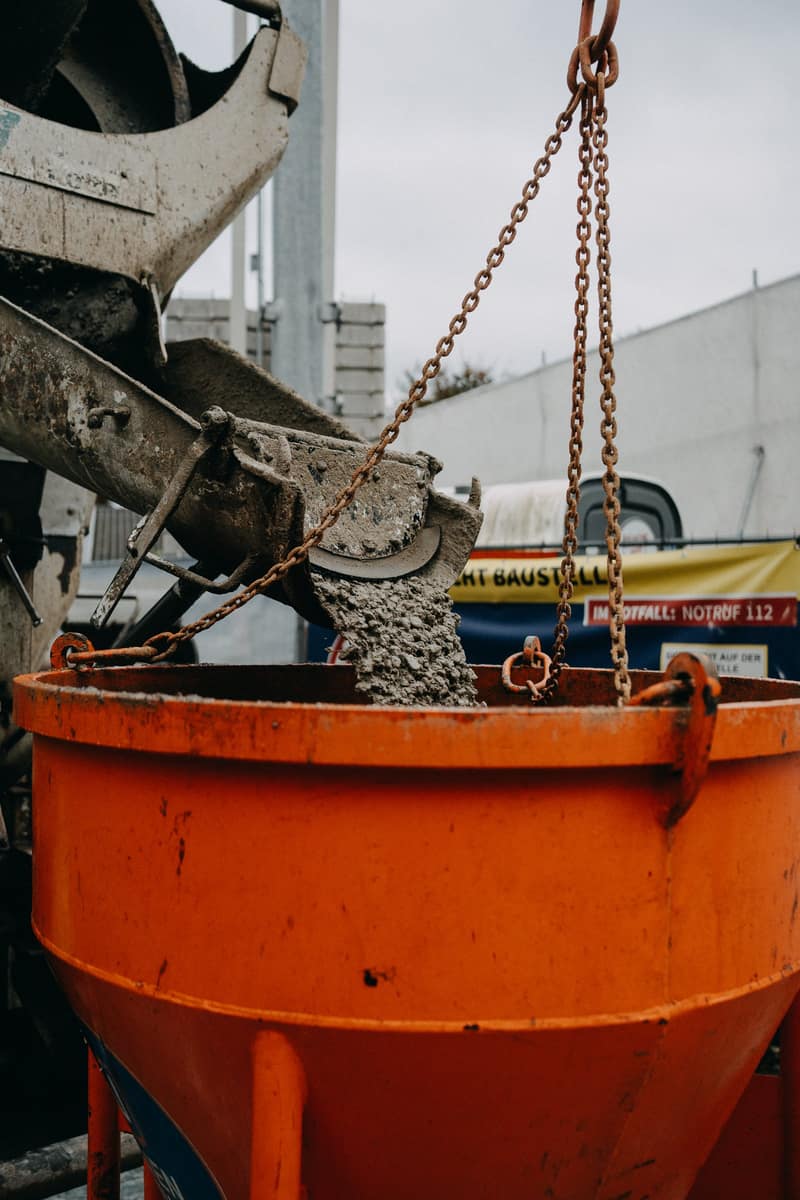 Fahrmischer befüllt einen orangefarbenen Krankübel auf einer Baustelle in Refrath