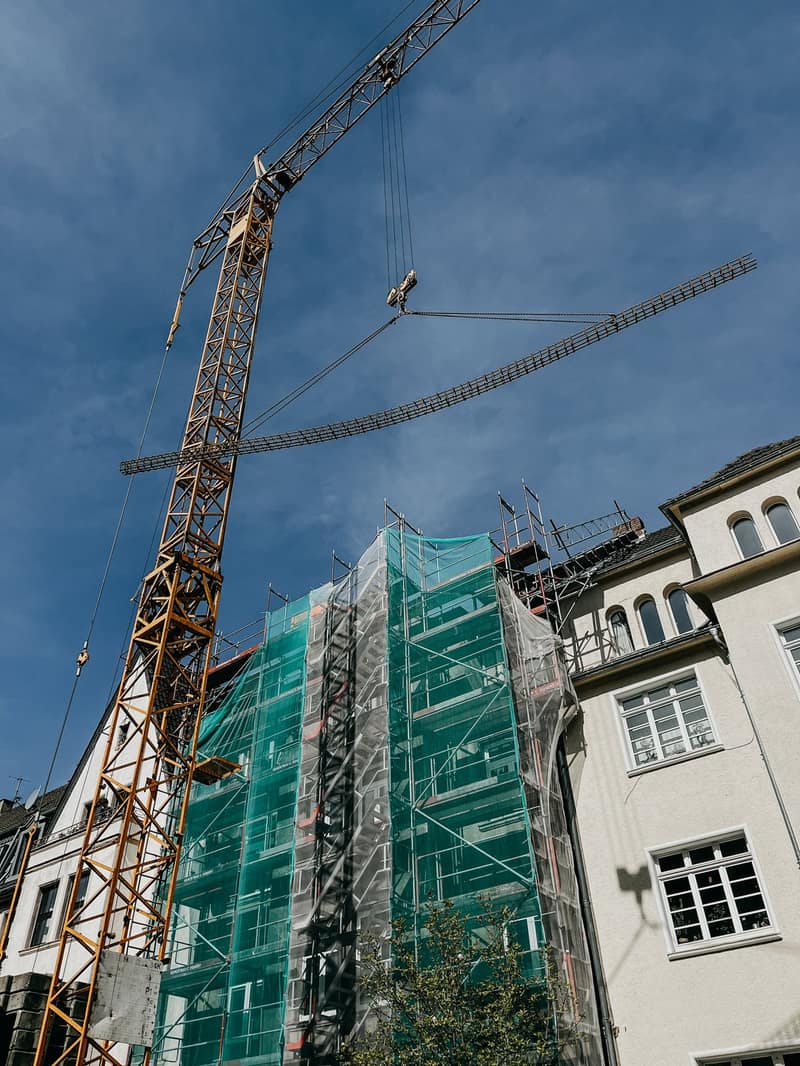 Baukran über einem eingerüsteten Altbau in der Stadt