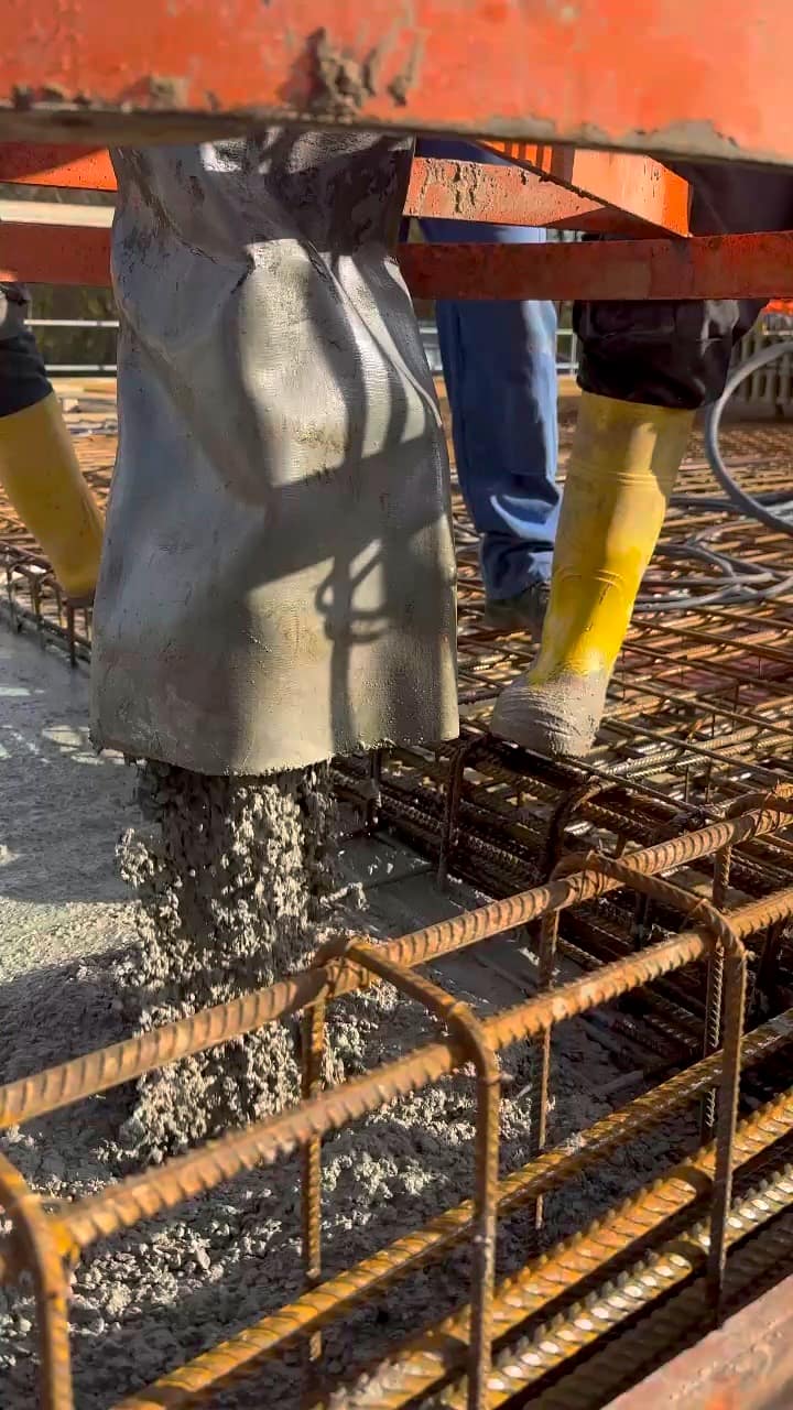 Beton fließt aus dem Krankübel in die Bewehrung