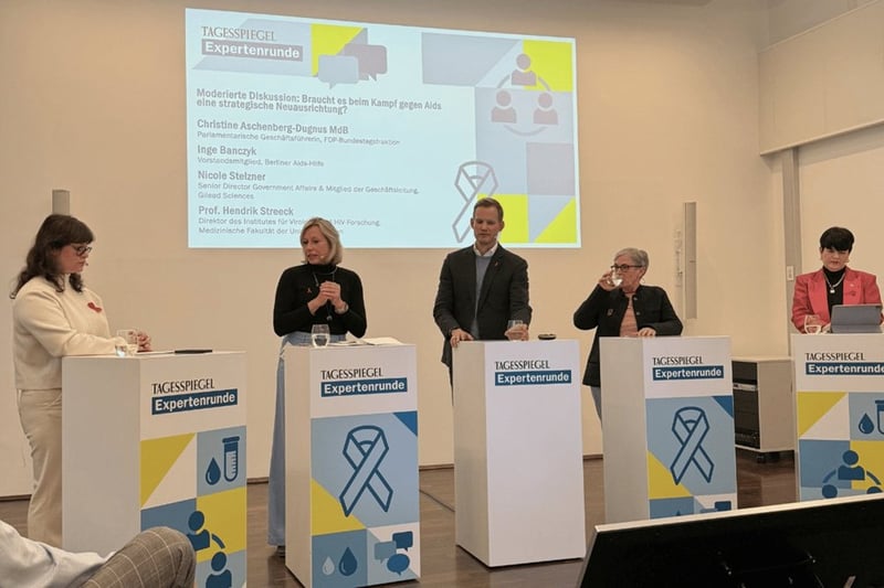 Personen an Stehpulten sprechen vor sitzendem Publikum.
