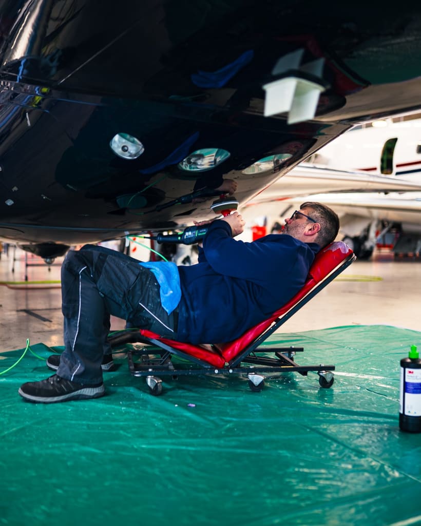 Techniker arbeitet liegend unter einem Geschäftsreiseflugzeug