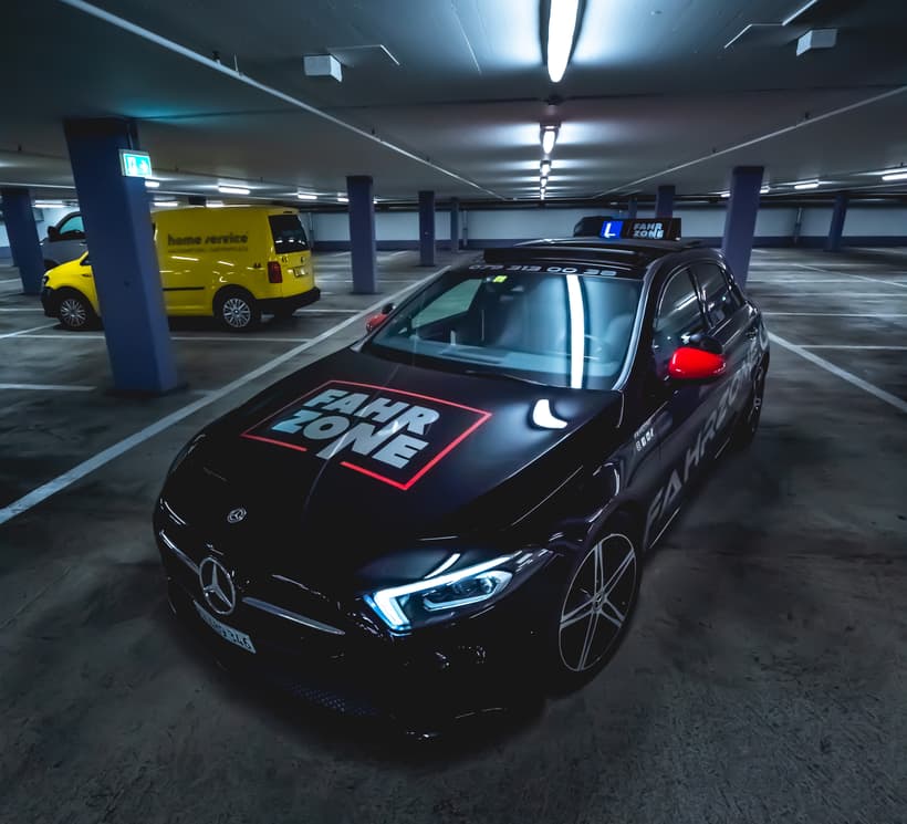 Schwarzer Mercedes-Benz mit rotem FAHRZONE-Schriftzug auf der Motorhaube in einer Tiefgarage.