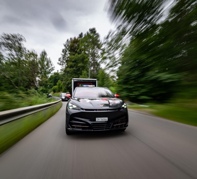 Junge Frau lehnt sich aus dem Fahrerfenster eines schwarzen Autos mit FAHRZONE-Schriftzug und hält einen Autoschlüssel.