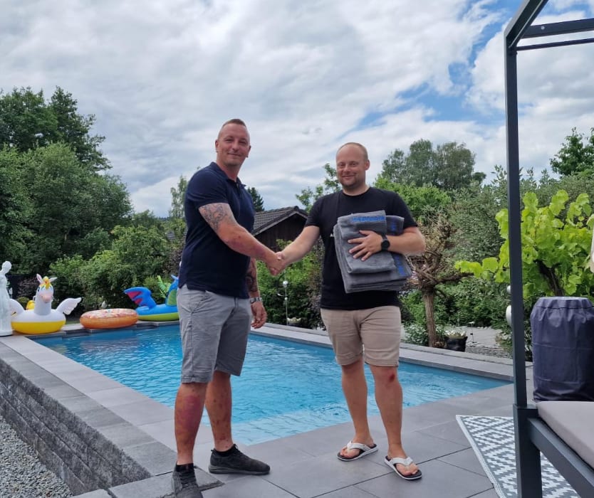 Arthur Hanschke übergibt einem Kunden die fertige Poolanlage per Handschlag, Poolbau Regensburg