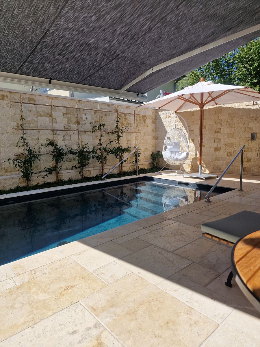 Betonpool mit Folienauskleidung und hellem Natursteinbelag bei Tag, Poolbau Hanschke GalaBau Regensburg