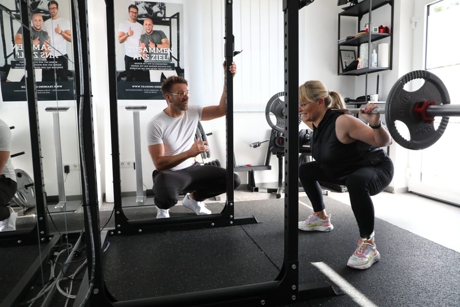 Mike sichert einen Kunden beim Langhantel-Training