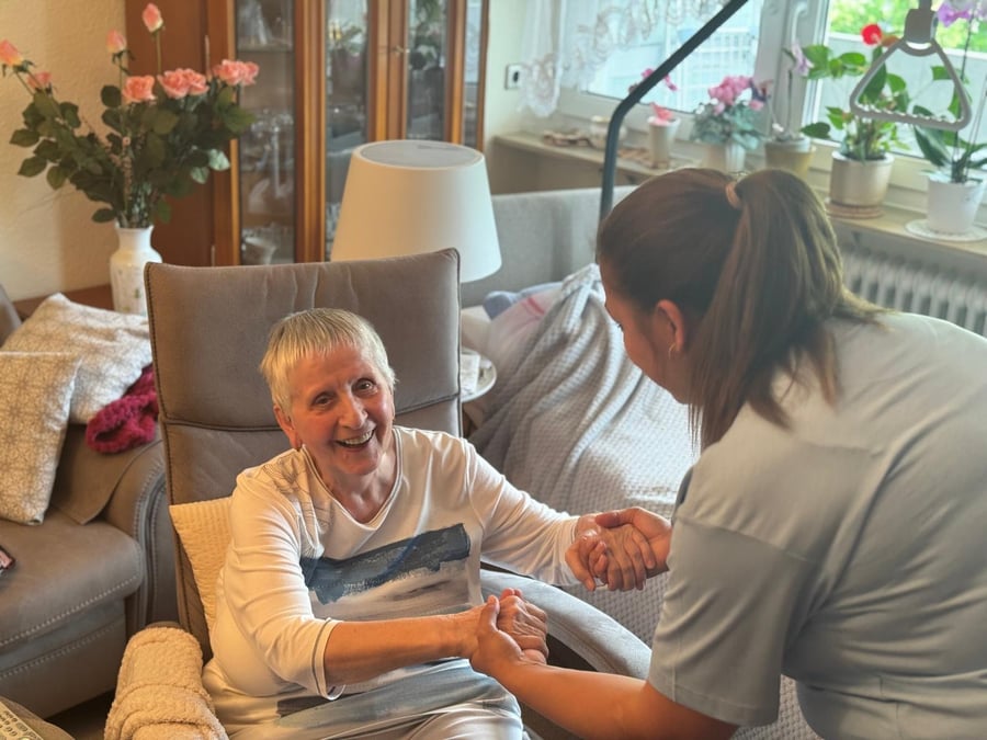 Pflegekraft von K&F im Gespräch mit einer Seniorin in ihrem Wohnzimmer – Beratungsbesuch zu Hause