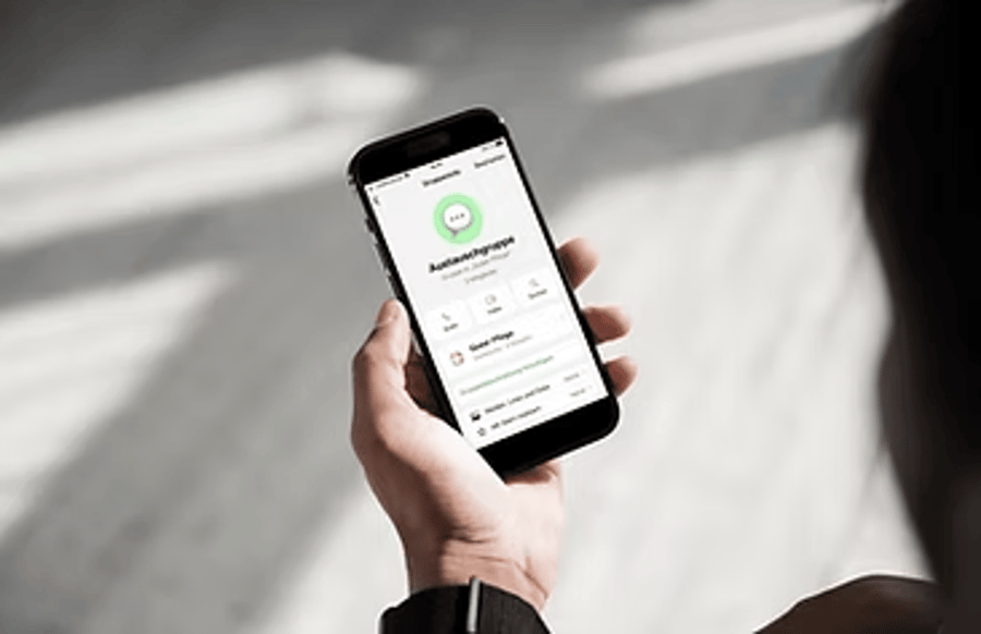 Eine Hand hält ein Smartphone mit einer Gruppen-Anzeige.