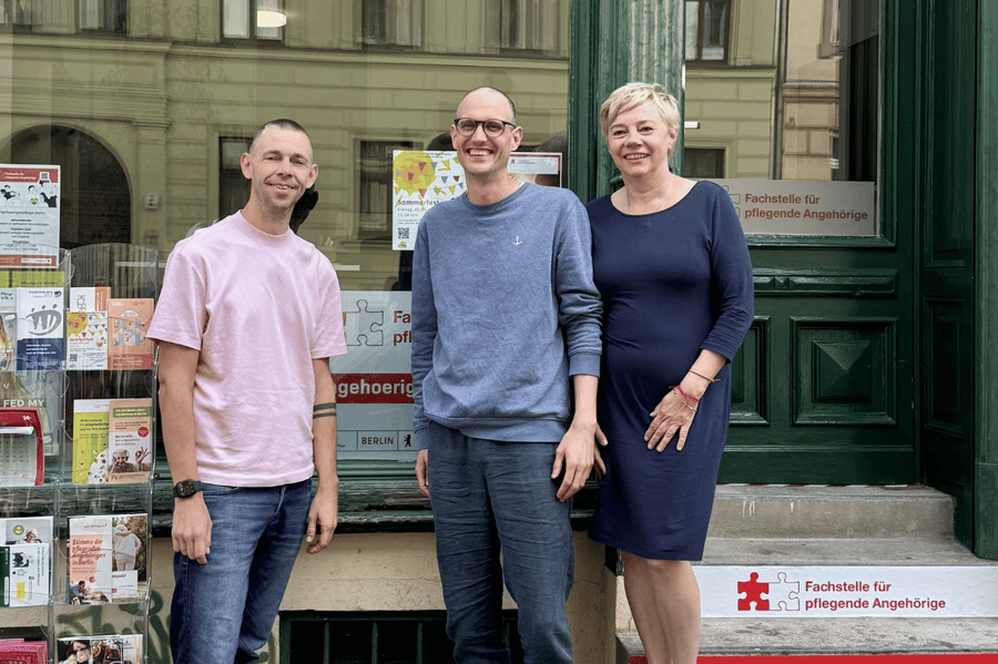 Drei Personen stehen vor dem Schaufenster der Fachstelle für pflegende Angehörige.