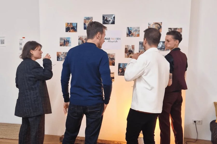 Personen betrachten eine Ausstellung an einer Wand.