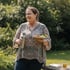 Woman in a printed shirt smiling while holding water and a healthy meal outdoors, promoting insulin resistance control