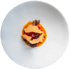 Gericht mit orangefarbener Soße, rotem Obst, beigefarbener Blätterteigschicht und Kräutern auf weißem Teller.