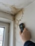 Feuchtemessung an einem Wasserfleck an Decke und Wand nach einem Wasserschaden