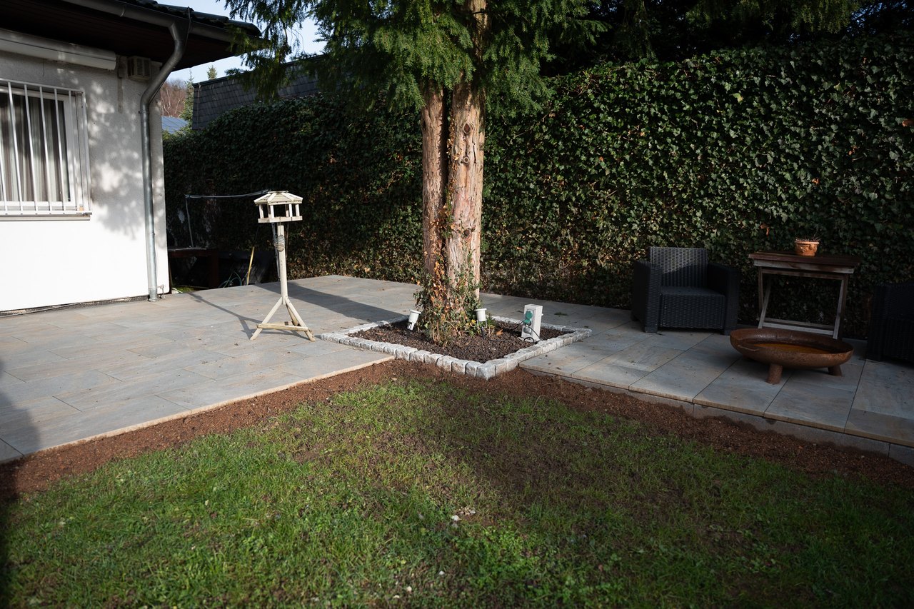 Pflegeleichter Garten mit Terrasse, Rasenfläche, Baum und Feuerstelle